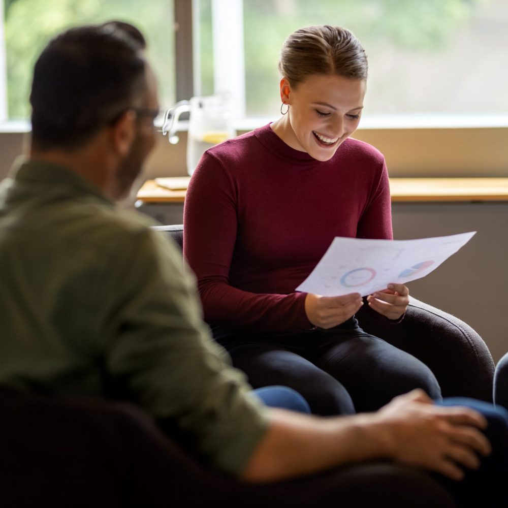 Smiling young businesswoman going over graphs during a meeting with a group of coworkers in an office